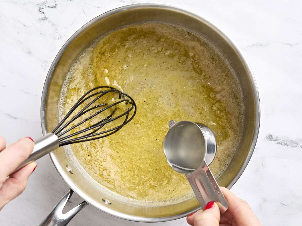 L'eau des pâtes réservée est fouettée dans le beurre fondu dans une poêle.