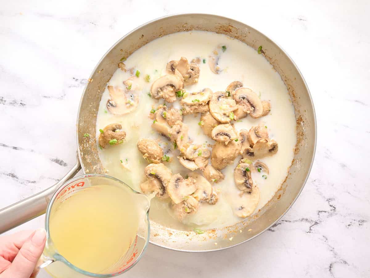 Bouillon de poulet versé dans une poêle avec des champignons et du lait.