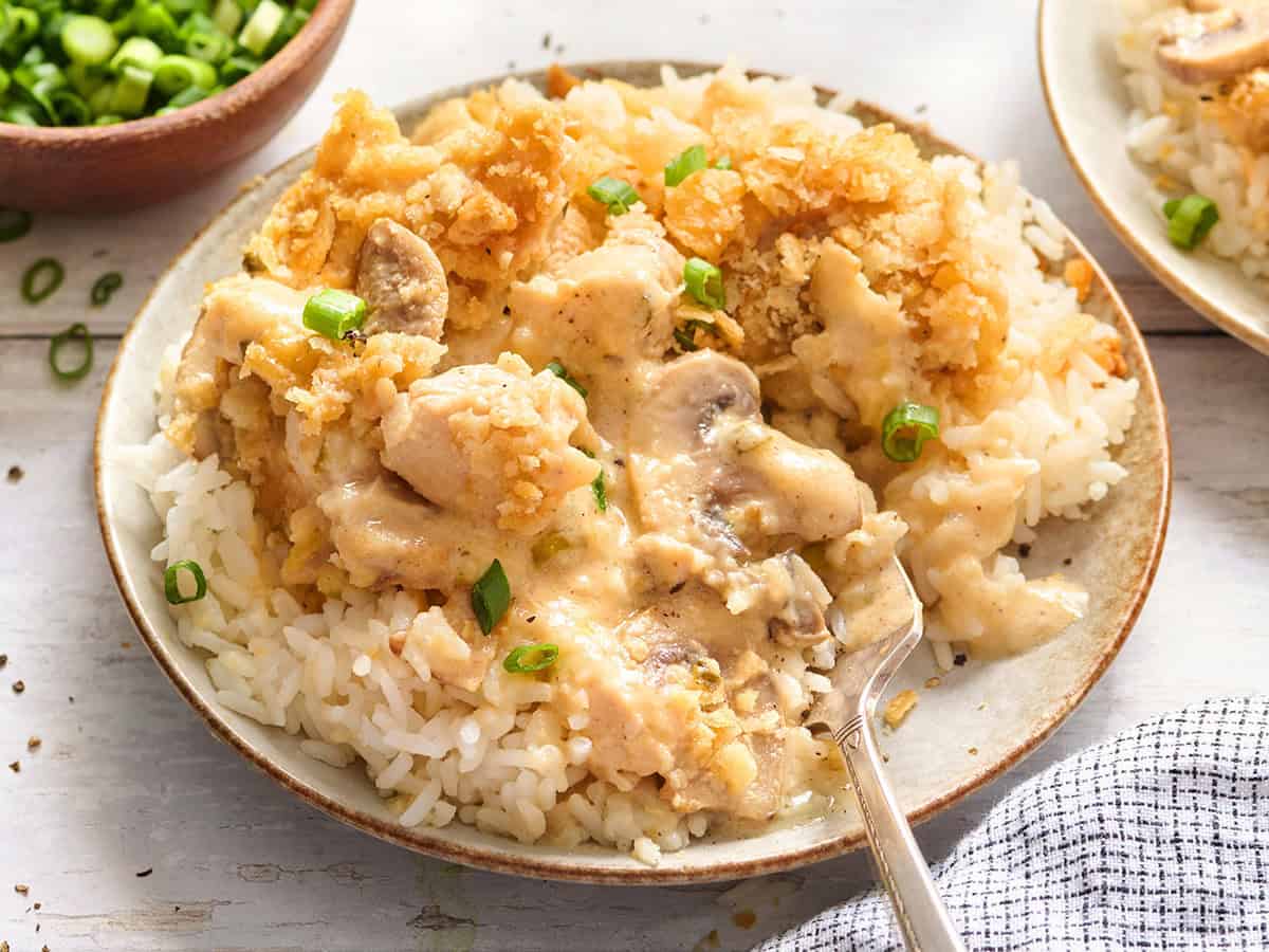 Vue latérale d'une cocotte de poulet d'un million de dollars sur une plaque avec du riz.