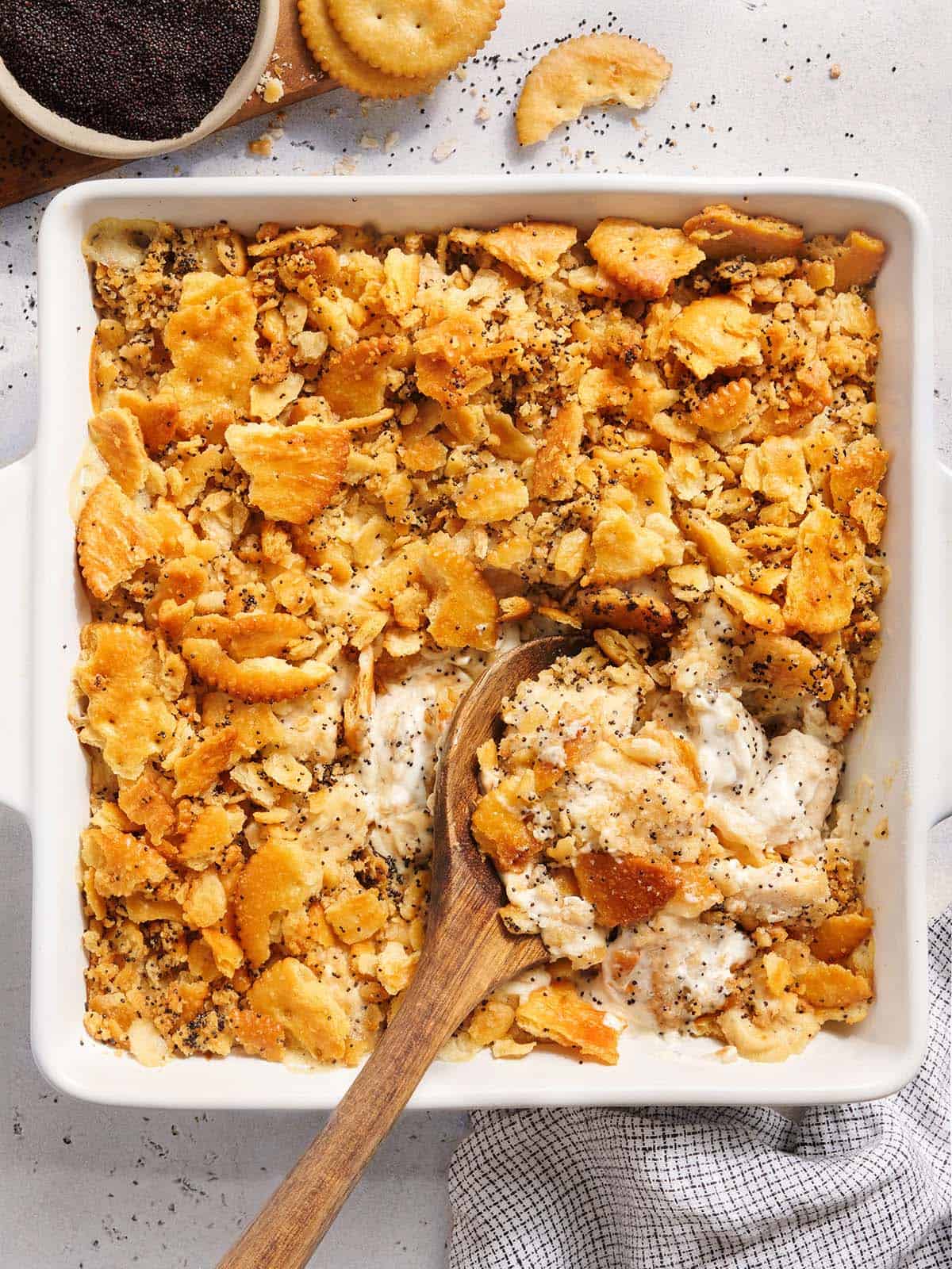 Vue aérienne d'une cocotte de poulet aux graines de pavot avec une cuillère en bois.