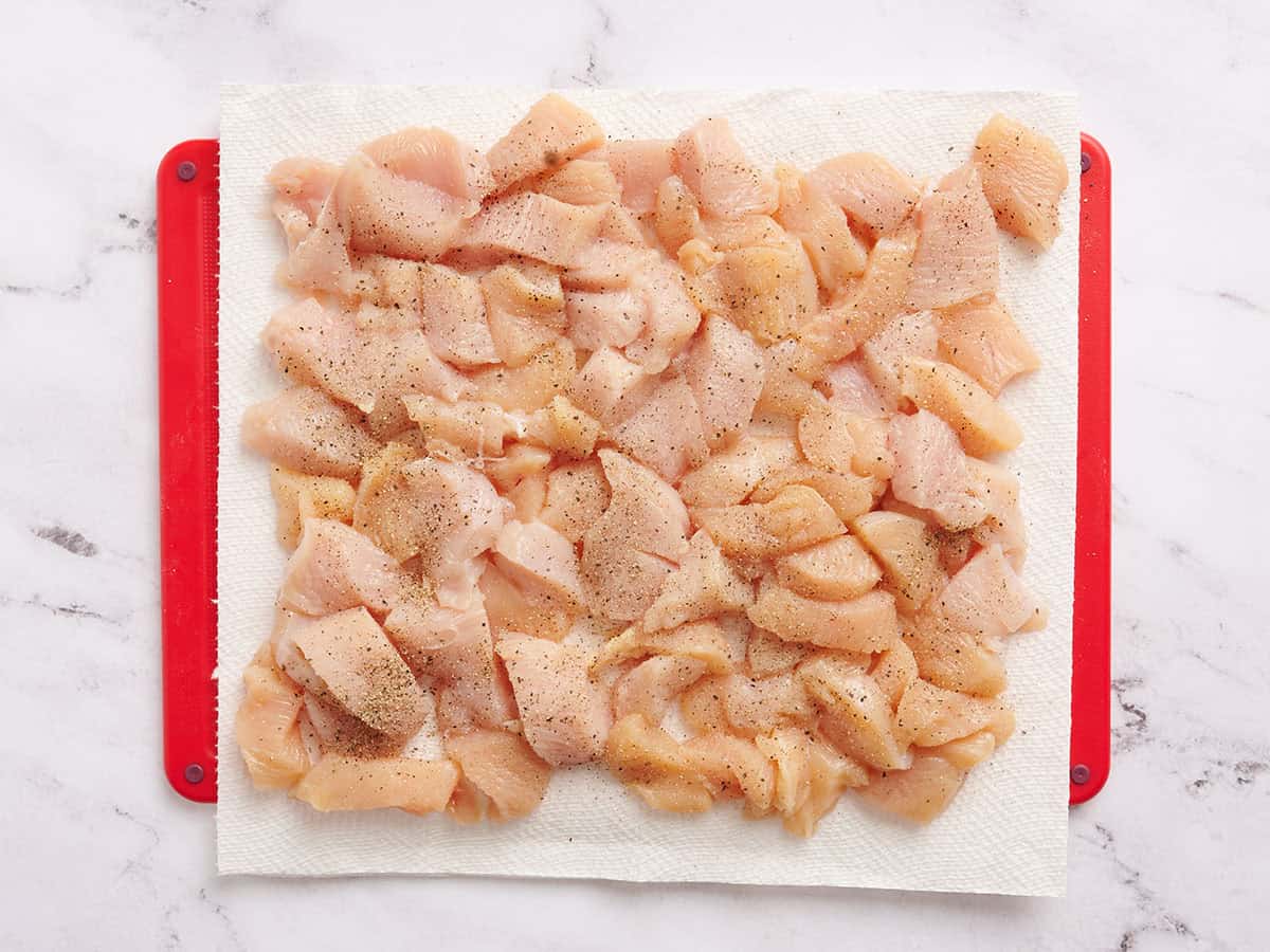 Poulet coupé en dés sur un tapis de découpe.