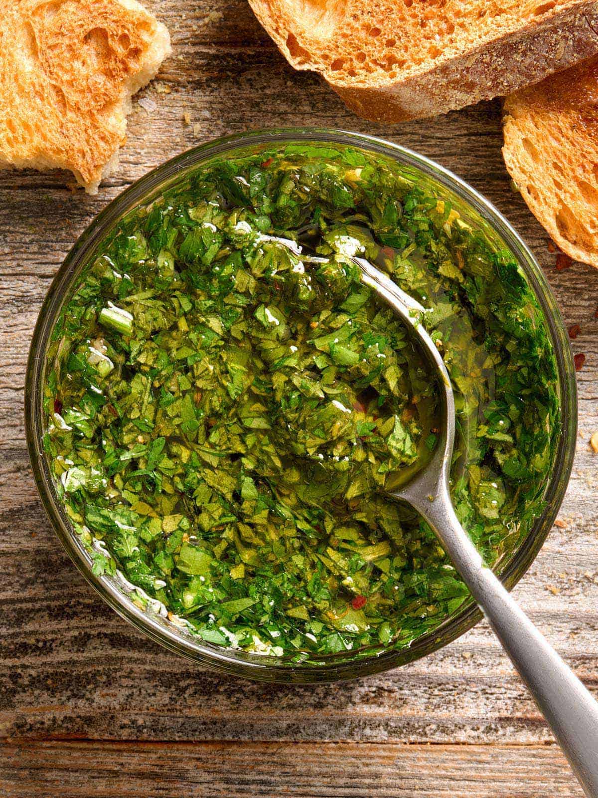 Vue aérienne d'un bol de sauce chimichurri avec une cuillère.