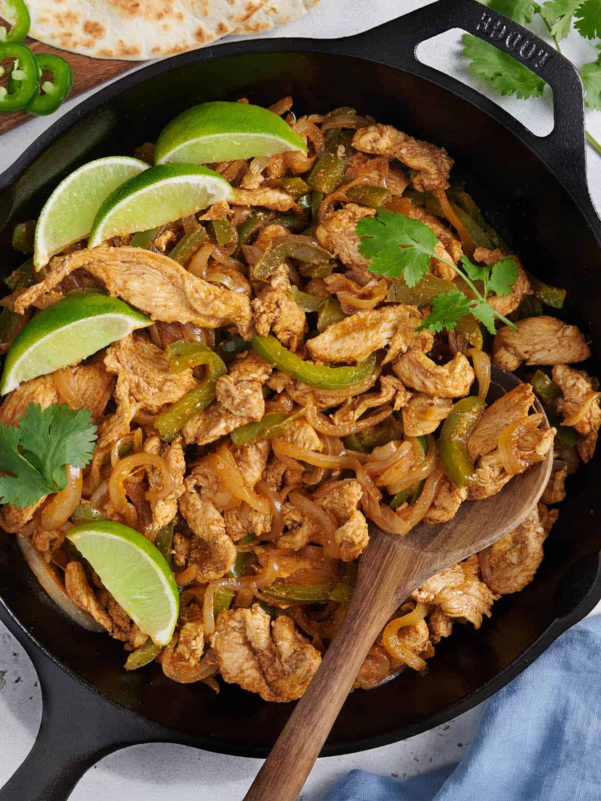 Vue aérienne d'une fajita au poulet sur la cuisinière remplissant une poêle avec une cuillère en bois.