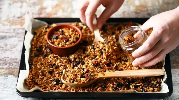 Granola maison fraîchement préparé sur une plaque à pâtisserie. Granola dans une cuillère en bois et dans un pot. Mise au point sélective. Concept de régime alimentaire sain. Régime céto.