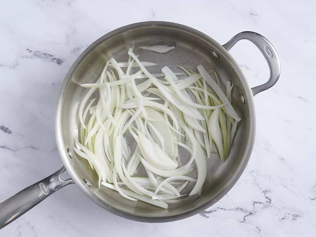 Oignons émincés dans une poêle.