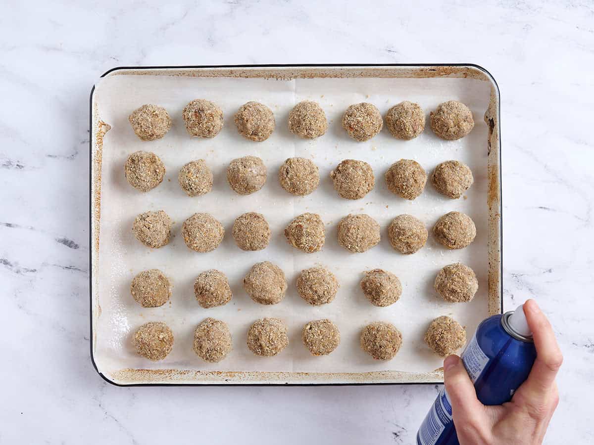 Boulettes de viande végétaliennes sur une plaque à pâtisserie vaporisées d'enduit à cuisson.