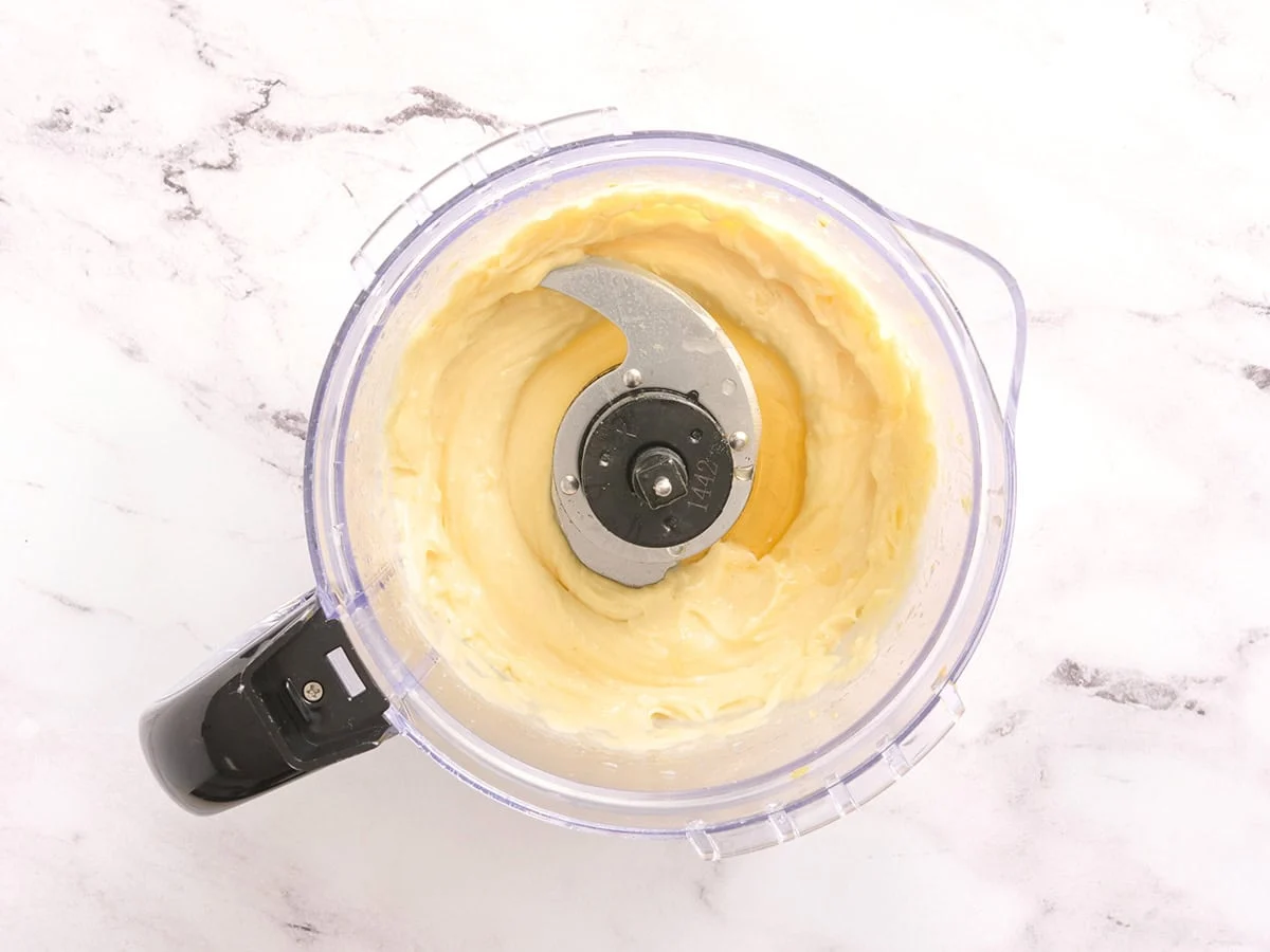 Miel et jus de citron ajoutés à un robot culinaire avec de l'aïoli à l'ail.