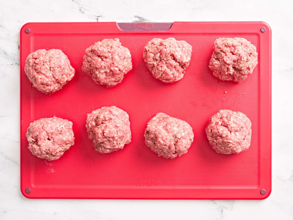 Bœuf haché formé en boules sur une planche à découper.