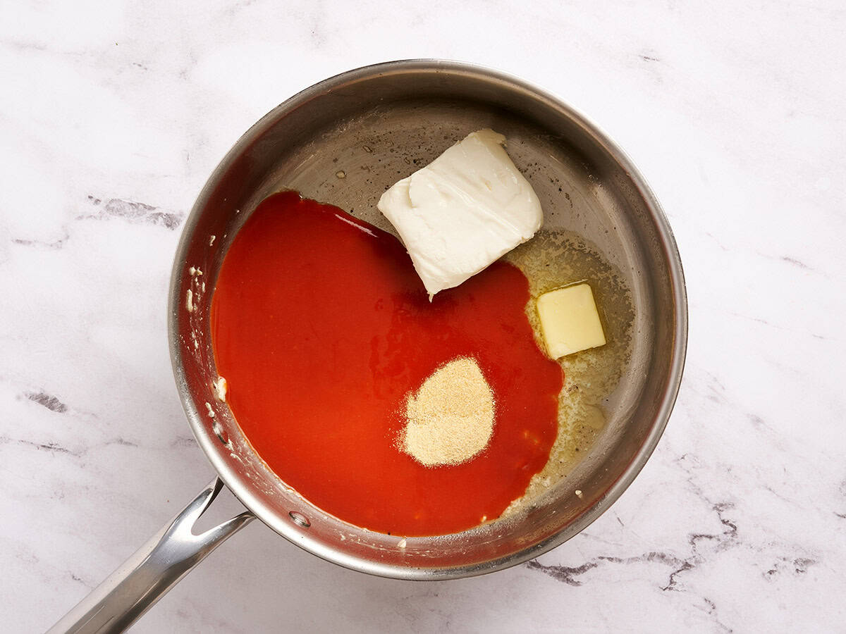 Sauce piquante, fromage à la crème, beurre et assaisonnements dans une poêle.