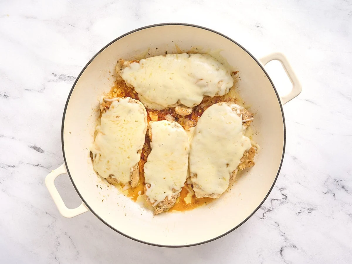 Culets de poulet garnis de mozzarella fondue dans une poêle.