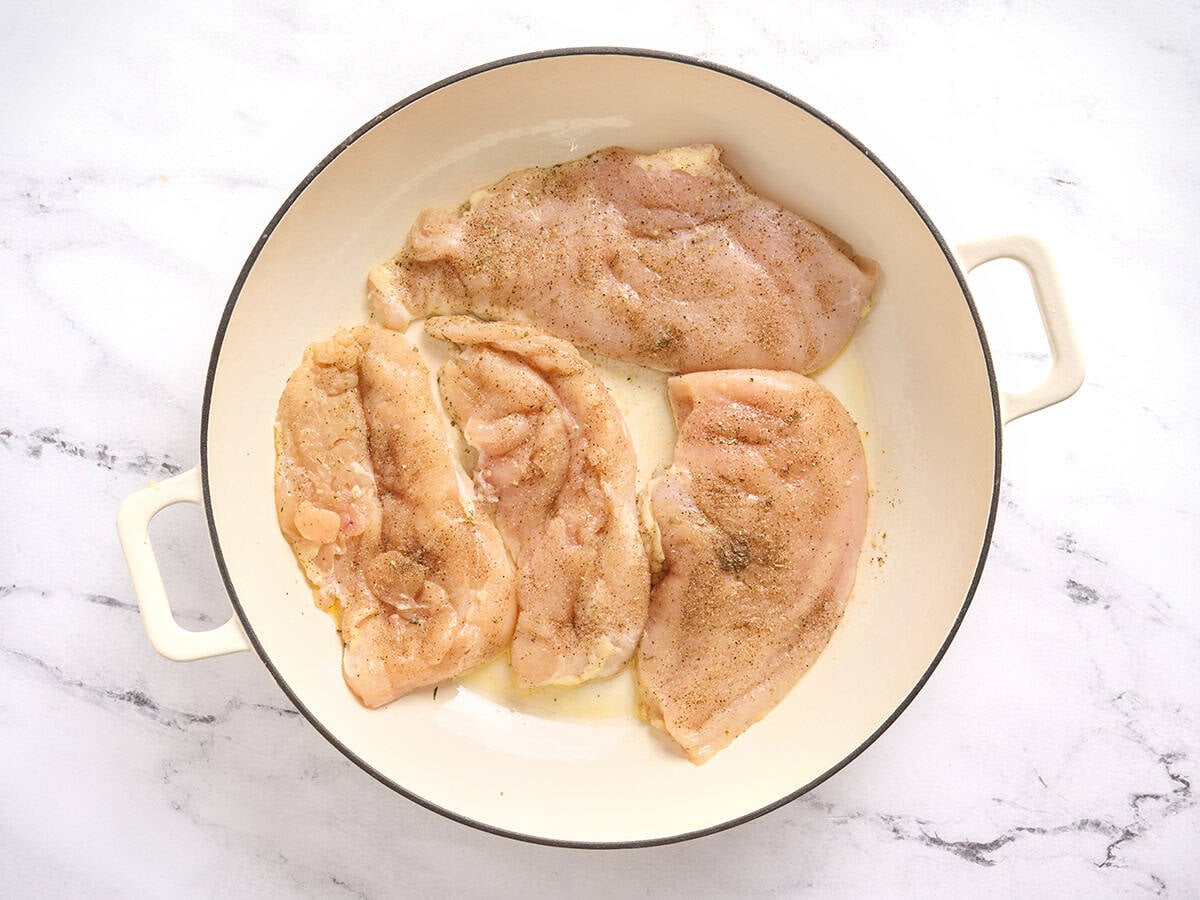 Escalopes de poitrine de poulet saisies dans une poêle.