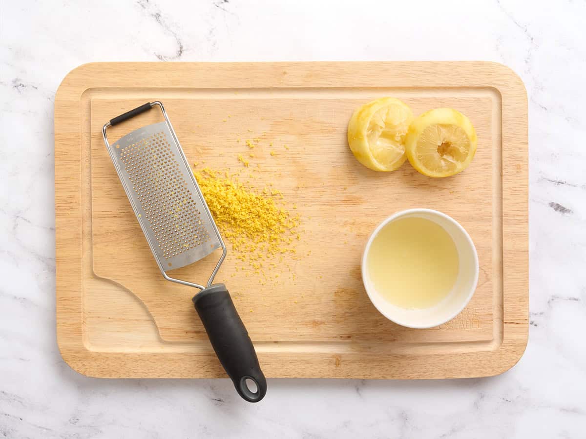 Citron pressé et zesté sur une planche à découper en bois.