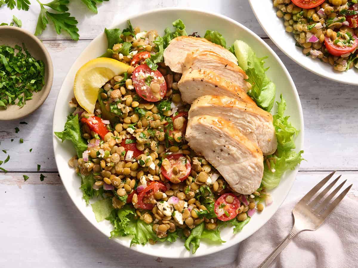 Vue aérienne d'un bol de salade de lentilles marinées et de poulet grillé.