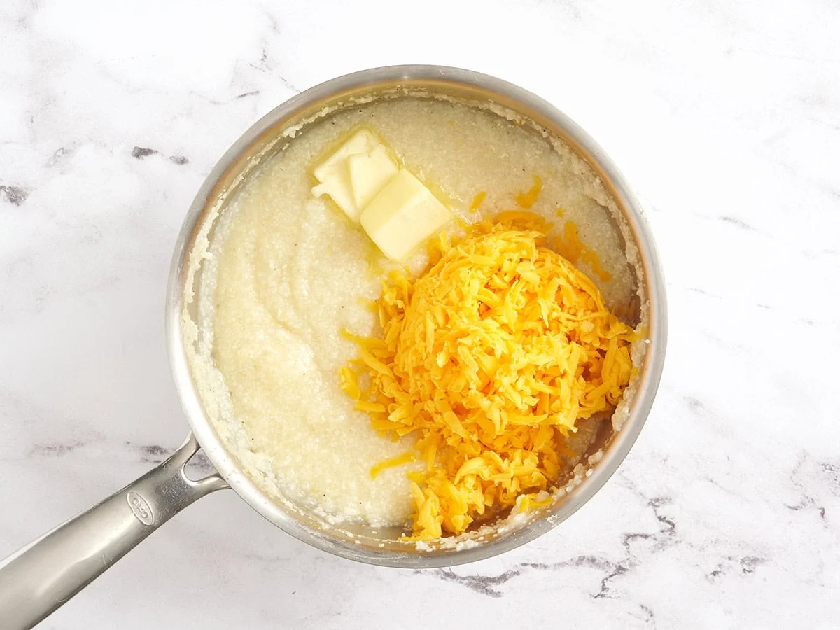 Fromage râpé et beurre ajoutés à une poêle de gruau.