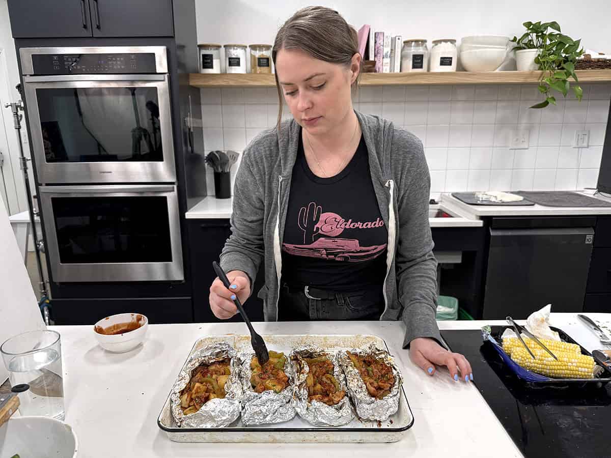 Une femme remplissant des sachets de poulet BBQ dans une cuisine.