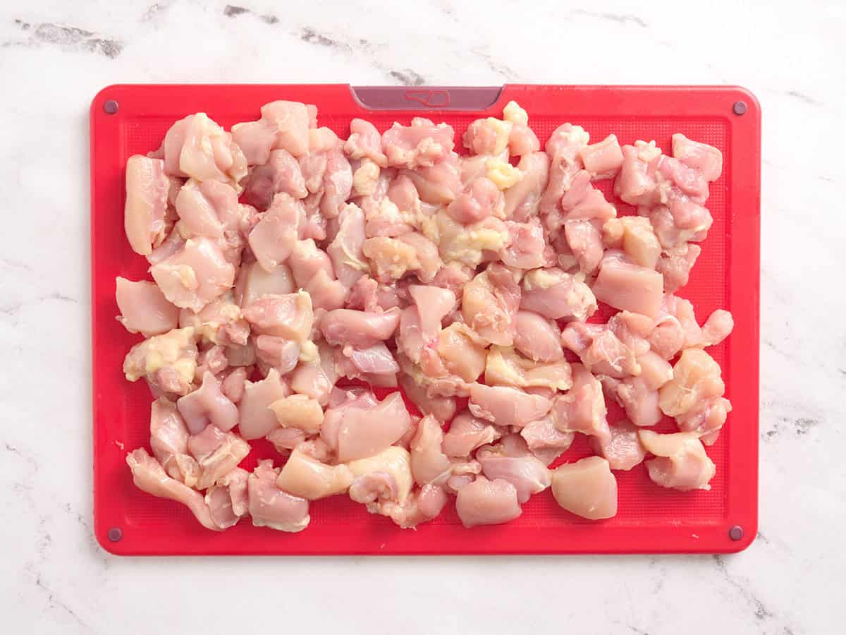 Poitrine de poulet coupée en dés sur une planche à découper.