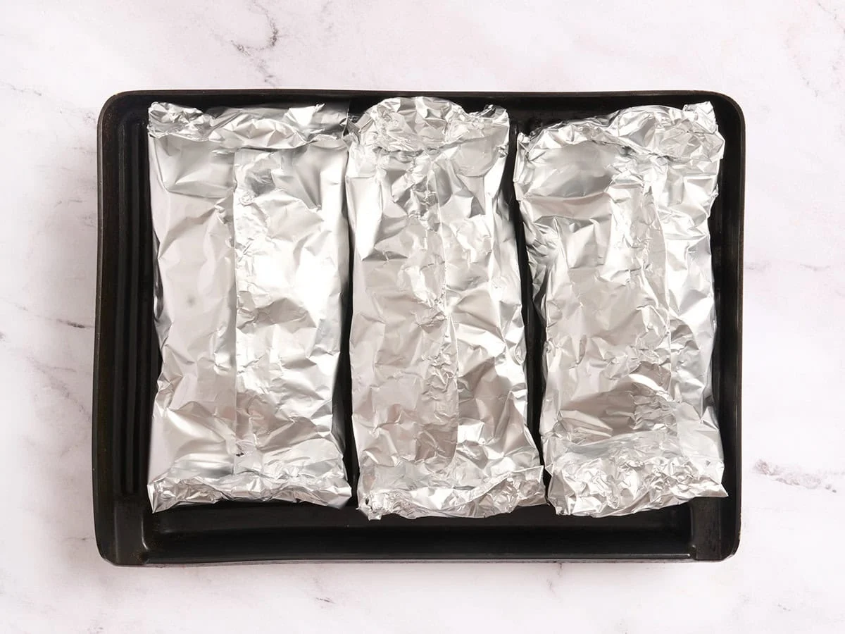 Trois paquets de papier d'aluminium sur un grill.
