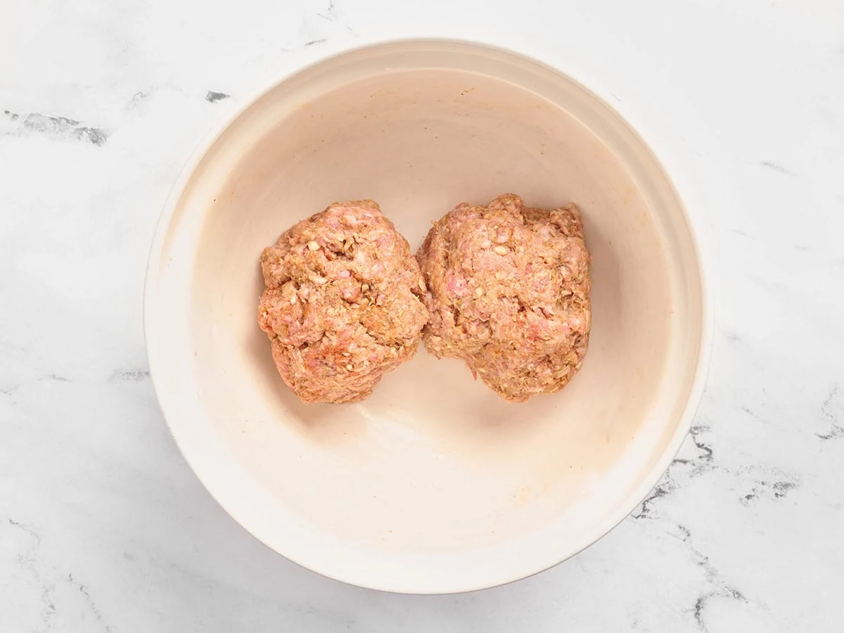Deux boulettes de bœuf haché assaisonné dans un bol.