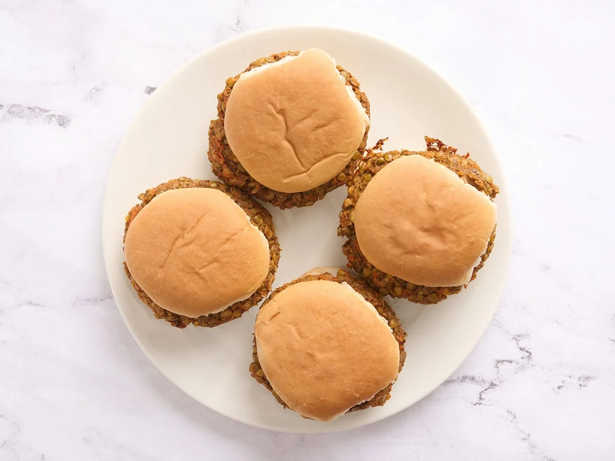 Vue aérienne de quatre hamburgers aux lentilles dans des petits pains à hamburger sur une assiette.