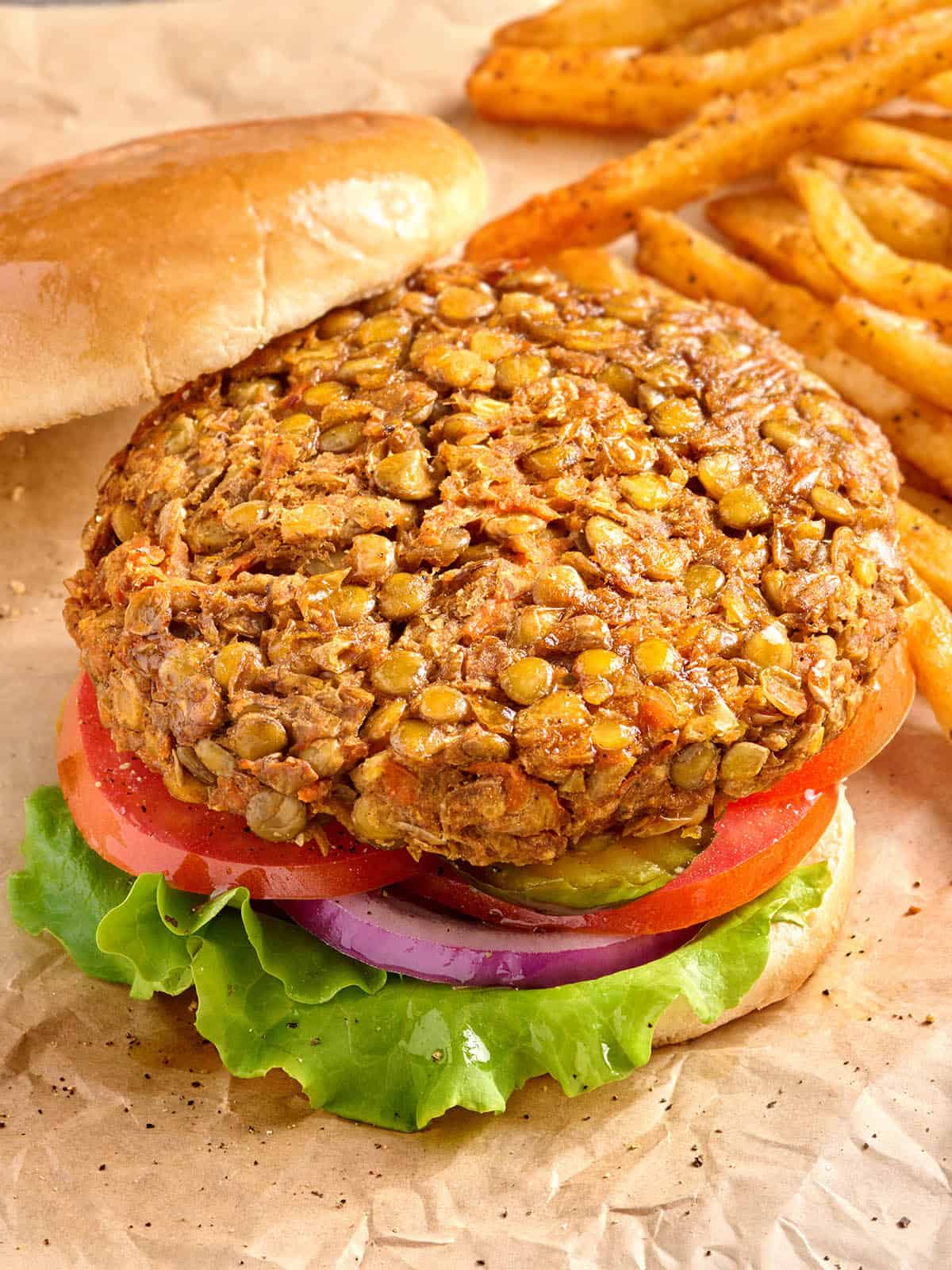 Vue latérale aérienne d'un hamburger aux lentilles dans un pain à hamburger, avec salade et pain supérieur retirés.