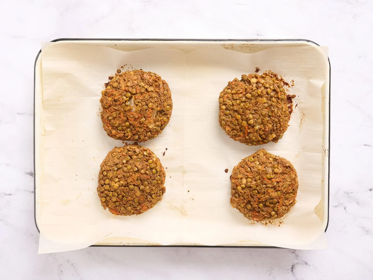 Burgers de lentilles faits maison fraîchement sortis du four sur une plaque à pâtisserie.