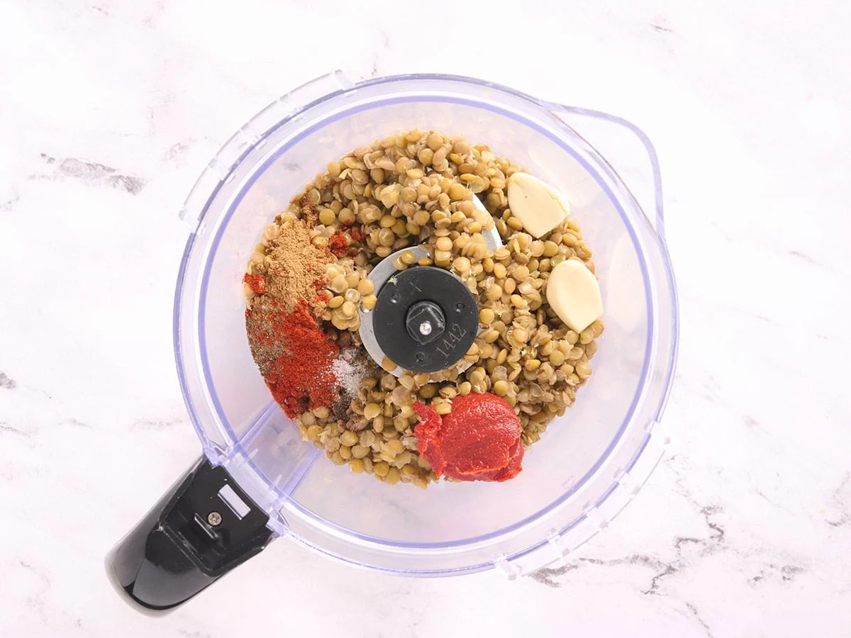 Lentilles cuites, épices, pâte de tomate et ail dans un robot culinaire.
