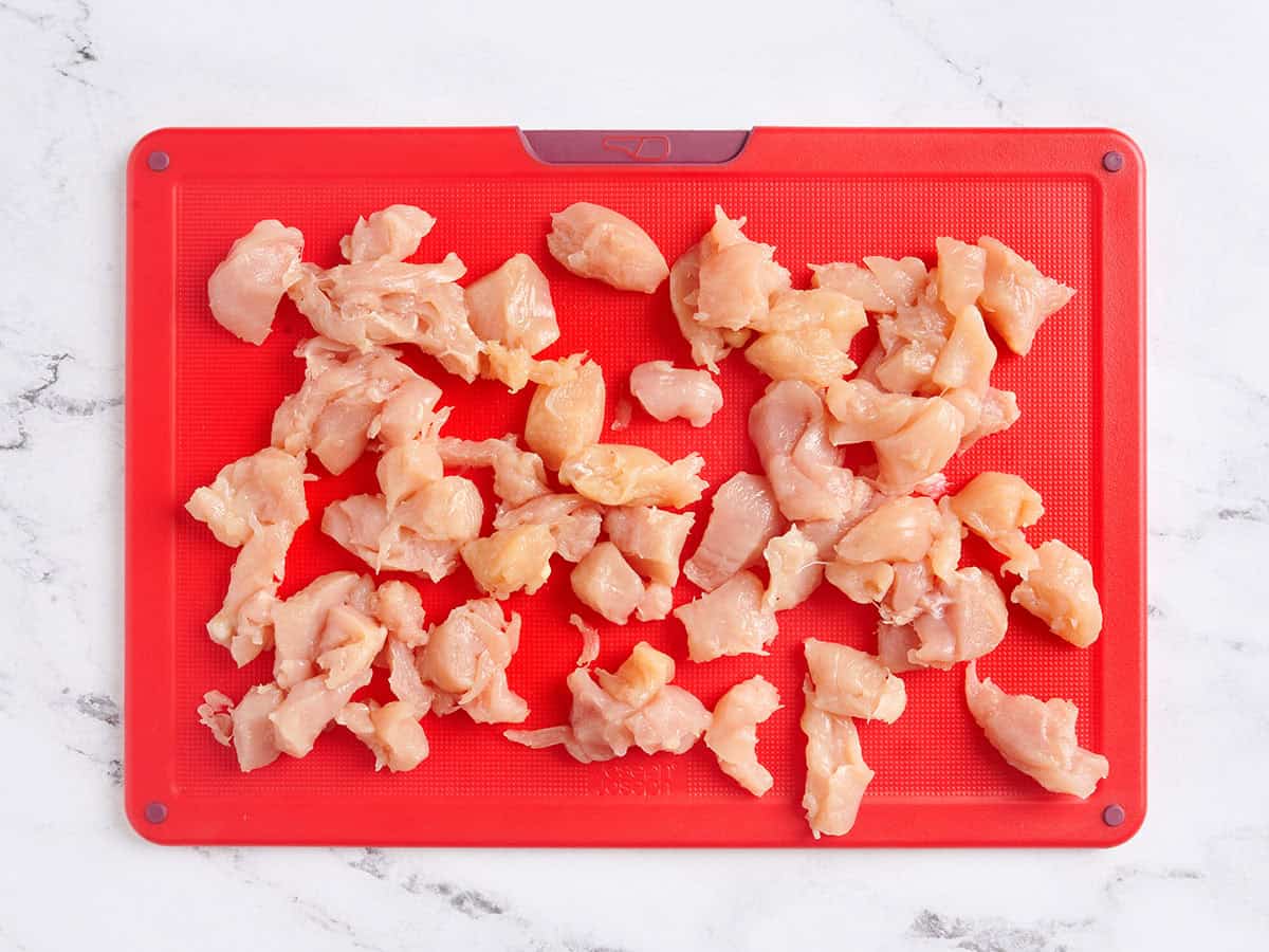 Filets de poulet coupés en morceaux sur une planche à découper.