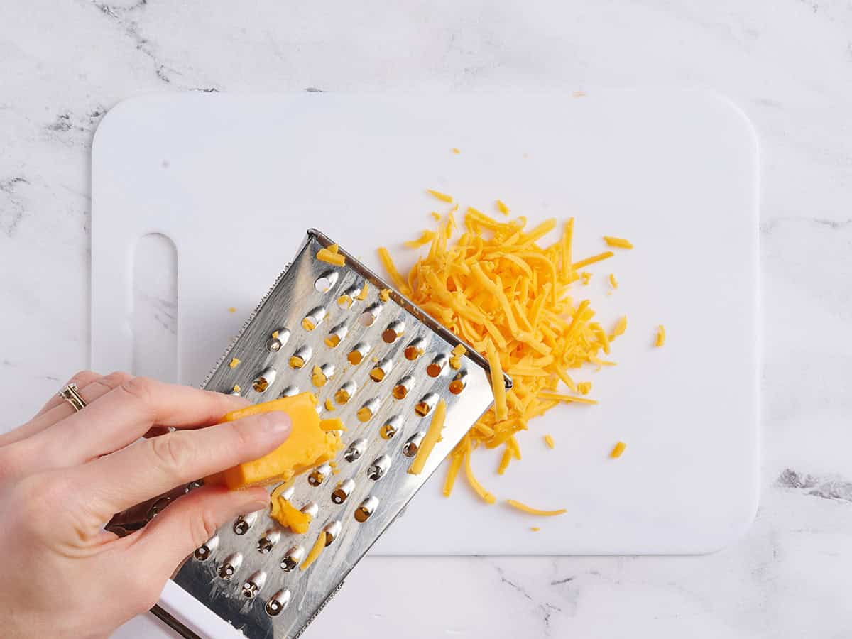 Une main utilisant une râpe pour râper le fromage.
