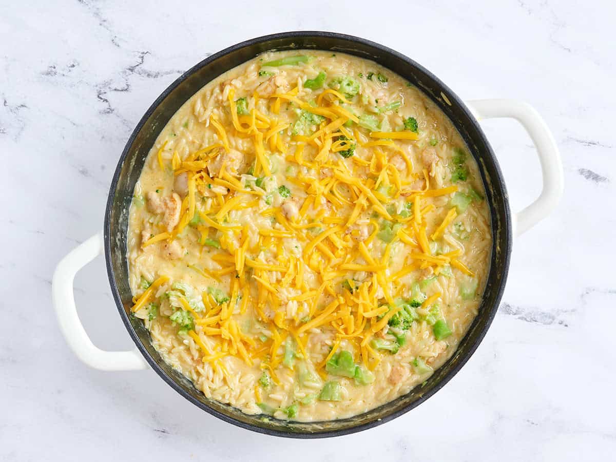 Fromage cheddar saupoudré sur une poêle de cocotte de poulet et de brocoli.