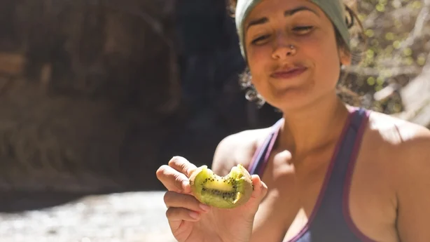 femme en bonne santé faisant de la randonnée et mangeant du kiwi