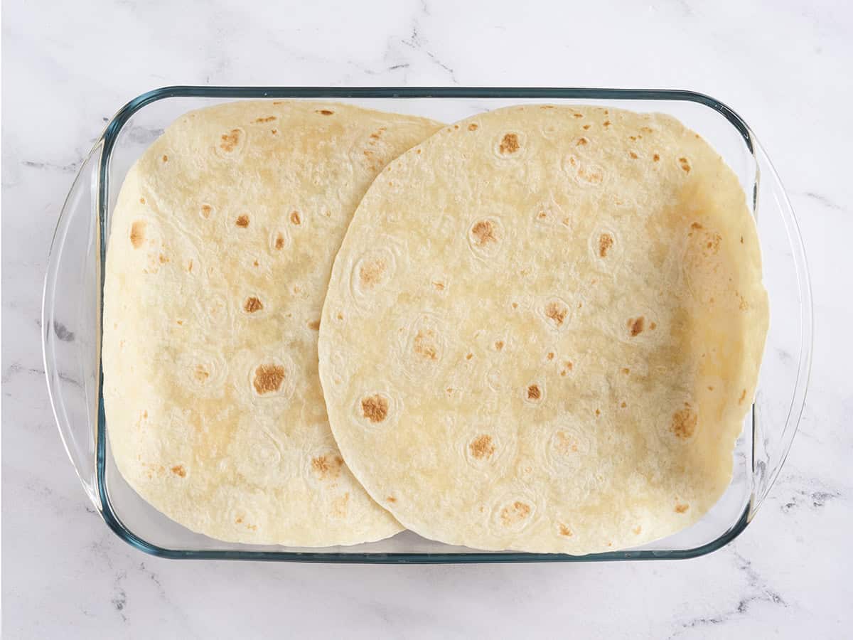 Deux grosses tortillas ajoutées à un plat allant au four.