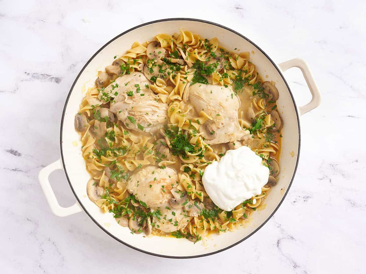 Crème sure et persil frais ajoutés à une poêle avec du poulet stroganoff.