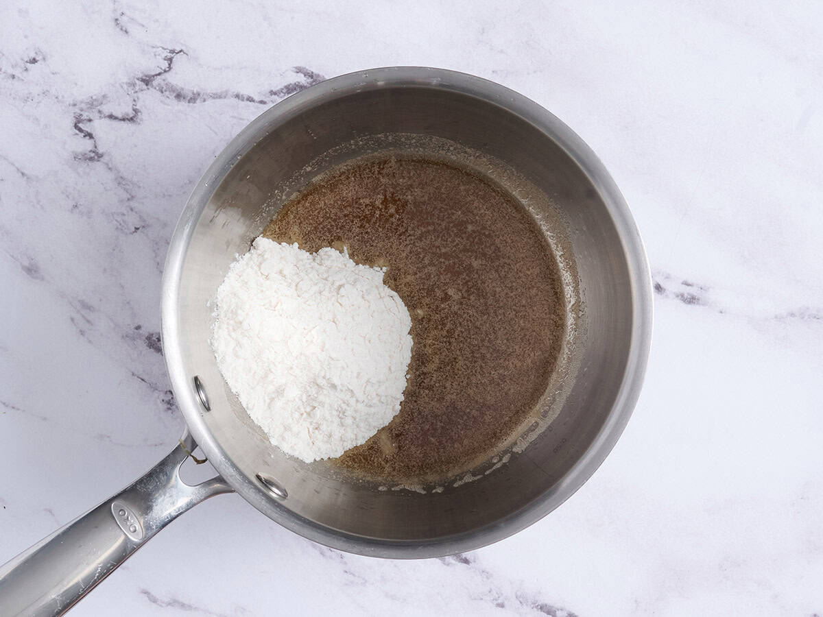 Farine ajoutée au beurre noisette dans une casserole.