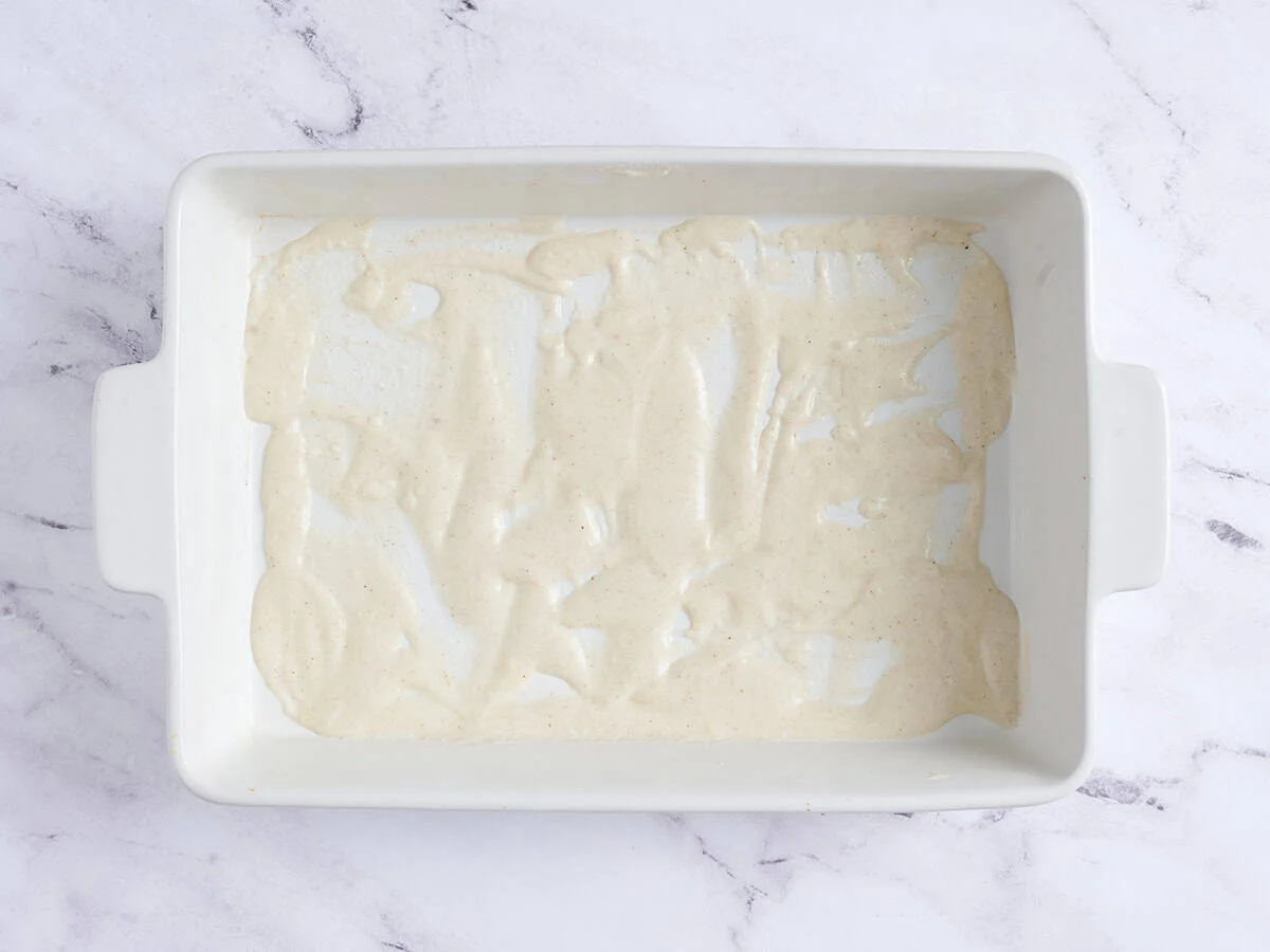 Sauce béchamel étalée dans un plat allant au four.