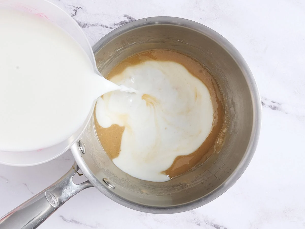 Lait ajouté à un roux au beurre noisette dans une casserole.