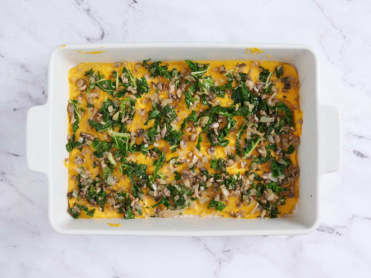 Garniture aux champignons et au chou frisé ajoutée sur la couche de nouilles pour une lasagne à la courge musquée.
