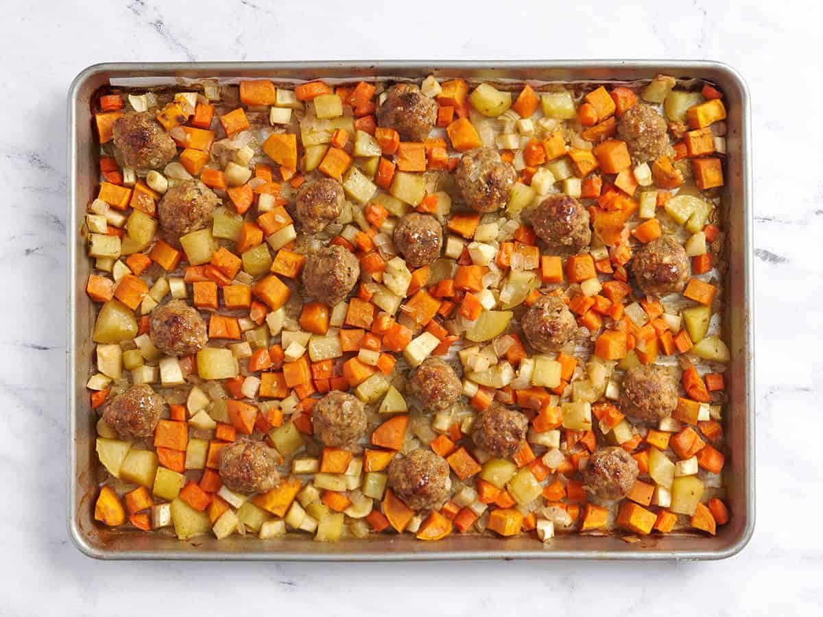 Boulettes de viande sur plaque finies avec légumes-racines sorties du four.