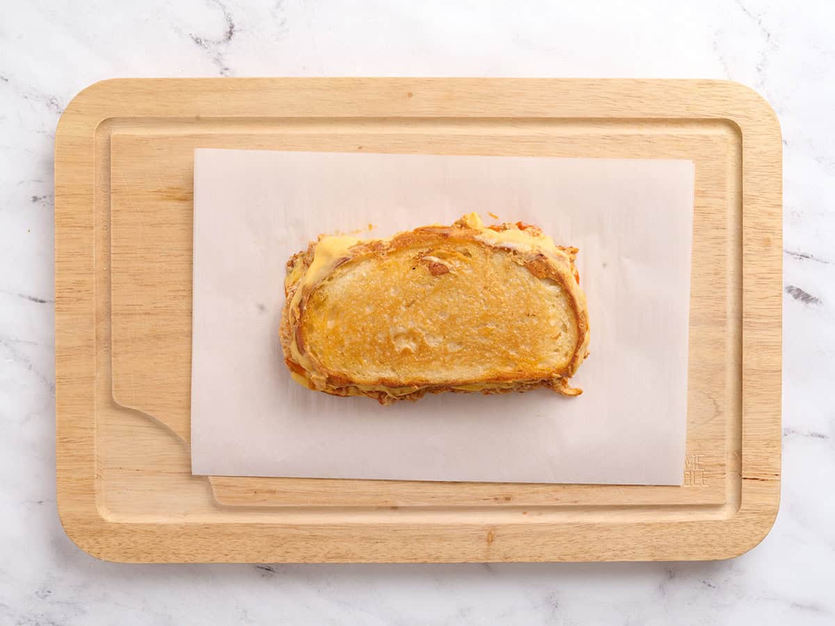 Sandwich au fromage grillé au poulet Buffalo fini sur une planche à découper en bois.