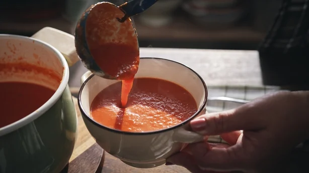 Une personne servant un bol de soupe aux tomates